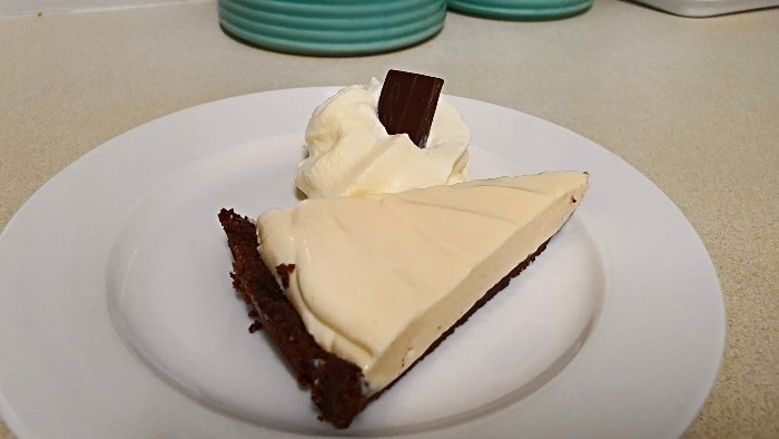 A slice of the World's Best Cheesecake served with cream and a wedge of chocolate